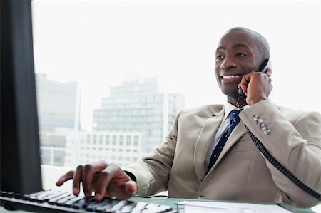 simsearch:400-05900712,k - Businessman on the phone while using a computer in his office Stock Photo - Budget Royalty-Free & Subscription, Code: 400-05900739