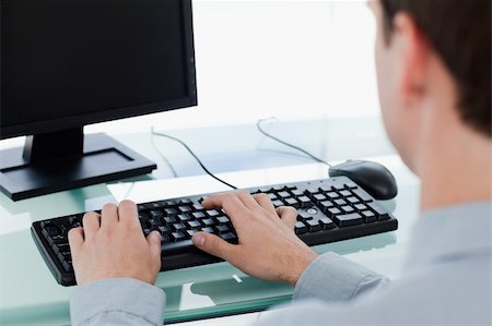 executives on table back - Back view of a manager working with a monitor in his office Stock Photo - Budget Royalty-Free & Subscription, Code: 400-05900850