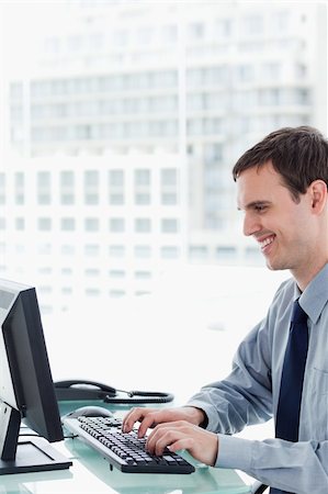 simsearch:400-08649785,k - Side view of a smiling office worker using a monitor in his office Stock Photo - Budget Royalty-Free & Subscription, Code: 400-05900875