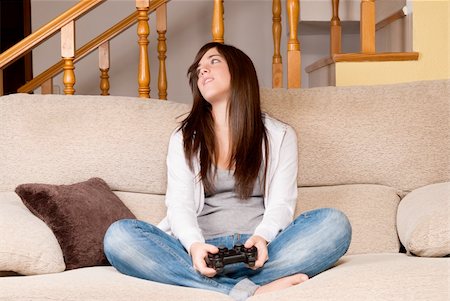 Young female lose playing video-games concentrating on sofa at home Stock Photo - Budget Royalty-Free & Subscription, Code: 400-05902201