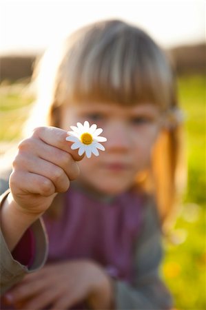 simsearch:400-06768635,k - Cute little girl outdoors on a green field with a flower Foto de stock - Royalty-Free Super Valor e Assinatura, Número: 400-05903025