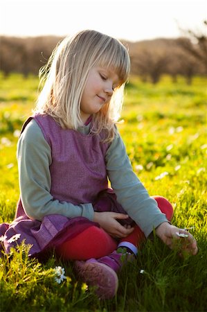 simsearch:400-06768635,k - Cute little girl outdoors sitting on a green field with flowers Foto de stock - Royalty-Free Super Valor e Assinatura, Número: 400-05903022