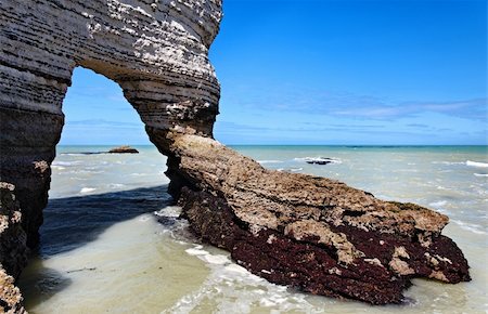 etretat - Natural arch in Etretat on the Upper Normandy coast in the North of France.Some of the rocks are formed from deposits of oysters and seaweed year after year. Foto de stock - Royalty-Free Super Valor e Assinatura, Número: 400-05914379