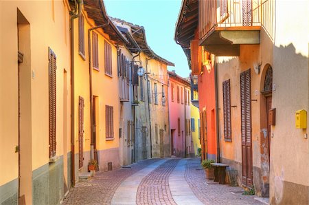Narrow paved street among old multicolored houses in town of Serralunga D'Alba in Piedmont, Northern Italy. Foto de stock - Royalty-Free Super Valor e Assinatura, Número: 400-05916126