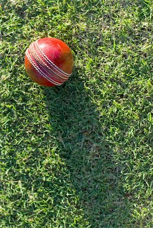 stockarch (artist) - A red cricket ball on green grass casting a long shadow down the length of the frame, with copyspace Stock Photo - Budget Royalty-Free & Subscription, Code: 400-05919763
