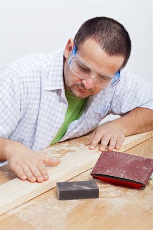 polishing wood - Man polishing wooden planck - checking results on workbench Stock Photo - Budget Royalty-Free & Subscription, Code: 400-05910487
