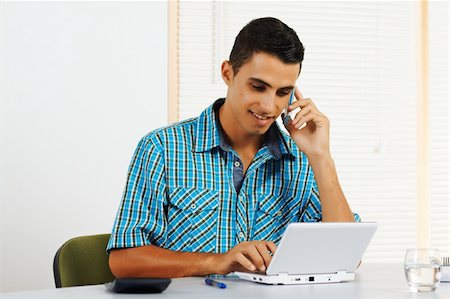 student latino business casual - Nice young man using a laptop while talking on the phone. Stock Photo - Budget Royalty-Free & Subscription, Code: 400-05910566