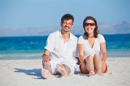 Happy young man and woman couple laughing and sitting on a deserted tropical beach with bright clear blue sky Foto de stock - Super Valor sin royalties y Suscripción, Código: 400-05911325