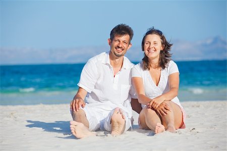 Happy young man and woman couple laughing and sitting on a deserted tropical beach with bright clear blue sky Foto de stock - Super Valor sin royalties y Suscripción, Código: 400-05911321