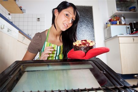 woman fetching a cake from an oven Foto de stock - Super Valor sin royalties y Suscripción, Código: 400-05911408