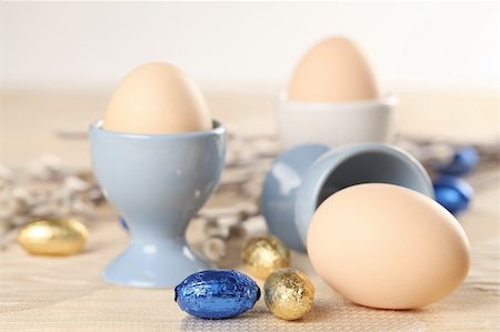 simsearch:400-04291976,k - Eggs in white and blue eggcups with catkins and little chocolate eggs in foil Photographie de stock - Aubaine LD & Abonnement, Code: 400-05920864
