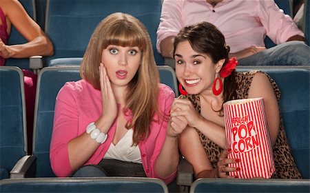 simsearch:400-06138368,k - Two amazed women with bag of popcorn watch movie in theater Fotografie stock - Microstock e Abbonamento, Codice: 400-05920988