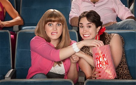 simsearch:400-06138368,k - Two anxious women enjoy movie with bag of popcorn Fotografie stock - Microstock e Abbonamento, Codice: 400-05920989