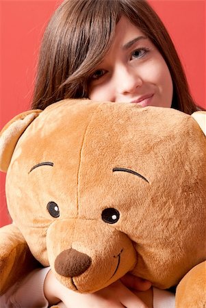furry teddy bear - Young woman embracing teddy bear sitting close-up on red background Stock Photo - Budget Royalty-Free & Subscription, Code: 400-05946589