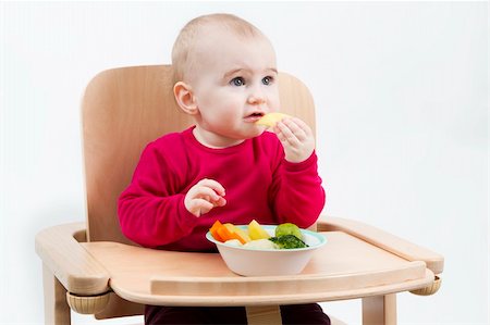 young child in red shirt eating vegetables in wooden chair. Foto de stock - Royalty-Free Super Valor e Assinatura, Número: 400-06065288