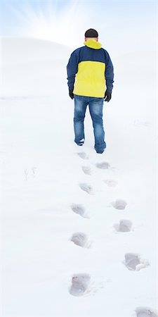 Man in yellow jacket walking on snow, footprints in snow, behind Stockbilder - Microstock & Abonnement, Bildnummer: 400-06065708