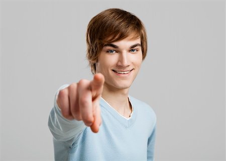 Portrait of a handsome young man pointing, over a gray background Photographie de stock - Aubaine LD & Abonnement, Code: 400-06065844