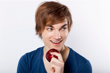 simsearch:400-05912400,k - Portrait of a casual young man with a happy face holding a apple, against a white wall Photographie de stock - Aubaine LD & Abonnement, Code: 400-06065854