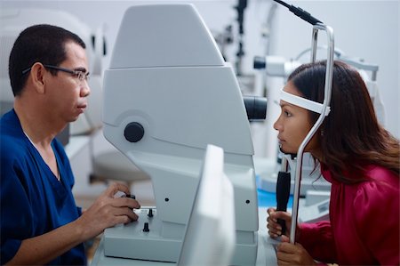 Asian doctor at work during eyesight exam to adult woman in hospital. Side view Stock Photo - Budget Royalty-Free & Subscription, Code: 400-06066265