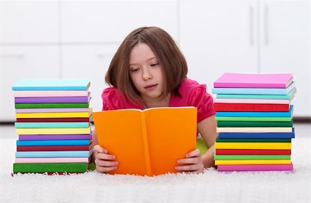 school girl holding pile of books - Young girl with colorful reading laying on the floor Stock Photo - Budget Royalty-Free & Subscription, Code: 400-06068508