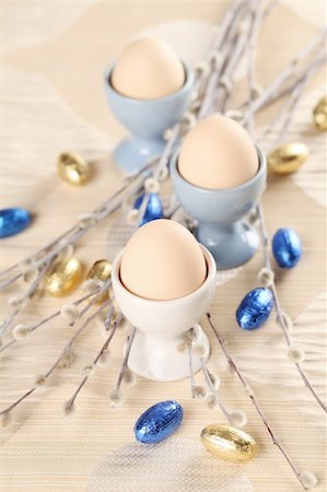 simsearch:400-04291976,k - Eggs in white and blue eggcups with catkins and little chocolate eggs in foil Photographie de stock - Aubaine LD & Abonnement, Code: 400-06069796