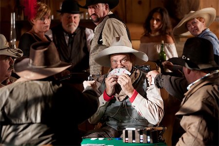 An old west cowboy hides behinds his cards after being caught cheating. Stock Photo - Budget Royalty-Free & Subscription, Code: 400-06061399