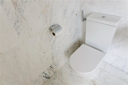 White toilet bowl in a bathroom with white marble tiles Foto de stock - Super Valor sin royalties y Suscripción, Código: 400-06062185