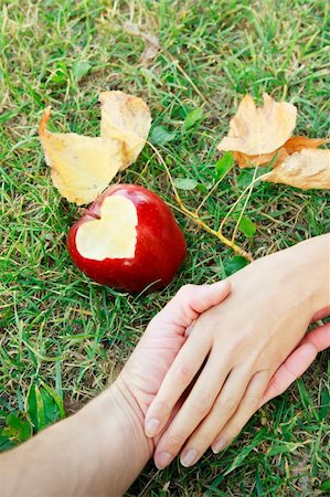 Romantic image with hands of  young couple of lovers on green grass with an apple with heart on it near and yellow leaves Stock Photo - Budget Royalty-Free & Subscription, Code: 400-06062355