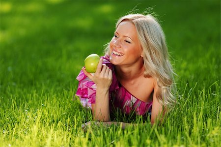 dreaming about eating - blonde holding an apple in his hand lying on green grass Foto de stock - Super Valor sin royalties y Suscripción, Código: 400-06062690