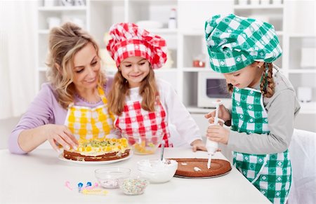 Woman and her daughters in the kitchen making a cake together Stock Photo - Budget Royalty-Free & Subscription, Code: 400-06063011