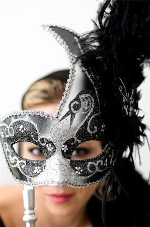 Woman holding metallic gray and black mask in front of her face. Focus is on mask and her face and eyes are blurred Stock Photo - Budget Royalty-Free & Subscription, Code: 400-06074280