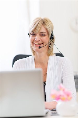 simsearch:400-03985399,k - Smiling senior business woman with headset working on laptop Photographie de stock - Aubaine LD & Abonnement, Code: 400-06076066