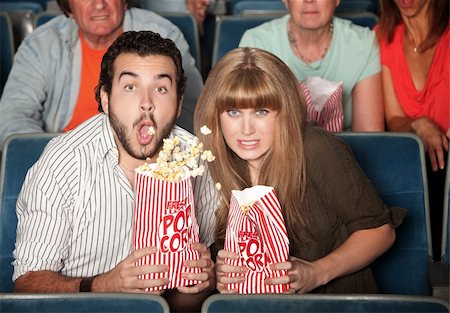 simsearch:400-06138368,k - Scared Caucasian couple in theater spill their popcorn Fotografie stock - Microstock e Abbonamento, Codice: 400-06076665