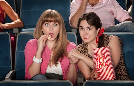 simsearch:400-06138368,k - Two anxious women watch movie with bag of popcorn Fotografie stock - Microstock e Abbonamento, Codice: 400-06076661