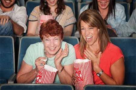 Two laughing women with popcorn bags at a picture show Stock Photo - Budget Royalty-Free & Subscription, Code: 400-06070074