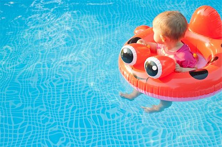 Small child in floatation device looking away while floating in a pool alone Photographie de stock - Aubaine LD & Abonnement, Code: 400-06072194