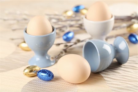 simsearch:400-04291976,k - Eggs in white and blue eggcups with catkins and little chocolate eggs in foil Photographie de stock - Aubaine LD & Abonnement, Code: 400-06073827