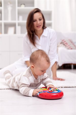 plastic toy family - Little girl playing on the floor with her mother in the background Stock Photo - Budget Royalty-Free & Subscription, Code: 400-06073988