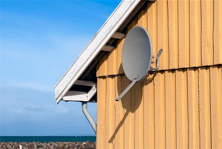Parabola satellite receiver on a wooden yellow house wall close to the sea in Denmark. Stock Photo - Budget Royalty-Free & Subscription, Code: 400-06081816