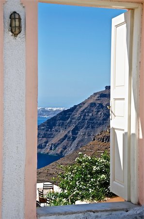 flowers greece - In opening the door is open can see the sky and mountains. At the bottom, surrounded by flowers can be seen a small cafe table. Stock Photo - Budget Royalty-Free & Subscription, Code: 400-06095116