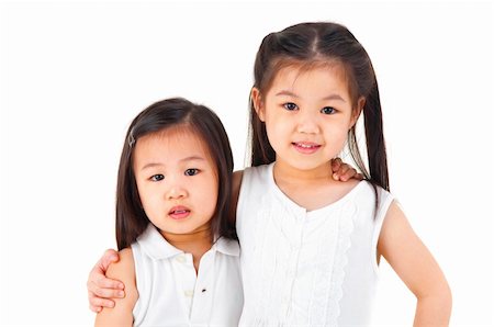simsearch:400-05352235,k - Asian sisters arms around on plain background Photographie de stock - Aubaine LD & Abonnement, Code: 400-06098654
