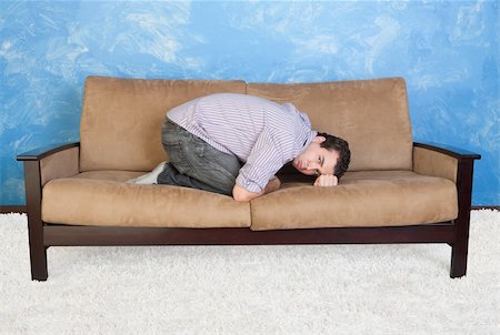 Upset young Caucasian man in fetal position on sofa Stock Photo - Budget Royalty-Free & Subscription, Code: 400-06090223