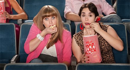 simsearch:400-06138368,k - Two amazed women eating popcorn in a theater Fotografie stock - Microstock e Abbonamento, Codice: 400-06090239