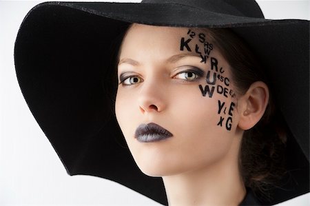 pretty and beautiful young lady with a creative make up made with letter on face and black hat and unusual shirt, she looks in to the lens with serious expression Stock Photo - Budget Royalty-Free & Subscription, Code: 400-06090484