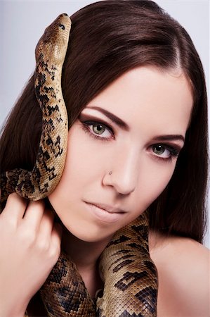 pitons - beautiful brunette girl with a snake around her head stares at the viewer Foto de stock - Super Valor sin royalties y Suscripción, Código: 400-06091490