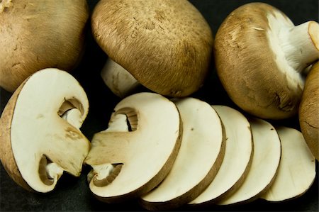 many small portabello mushrooms, also known as chestnut mushrooms on a dark background Foto de stock - Royalty-Free Super Valor e Assinatura, Número: 400-06091670