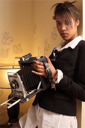 Photo of a beautiful young woman of African descent, holding a vintage 4x6 film camera. Stock Photo - Budget Royalty-Free & Subscription, Code: 400-06093102