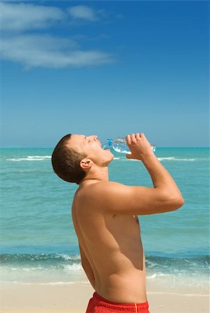 Young handsome man drinking water from bottle on the beach Stock Photo - Budget Royalty-Free & Subscription, Code: 400-06105748
