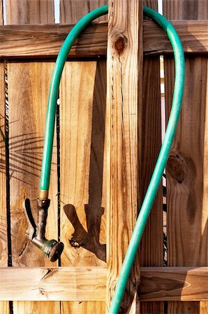 photo picket garden - Wood fence and garden hose with spray nozzle. Photographie de stock - Aubaine LD & Abonnement, Code: 400-06106387