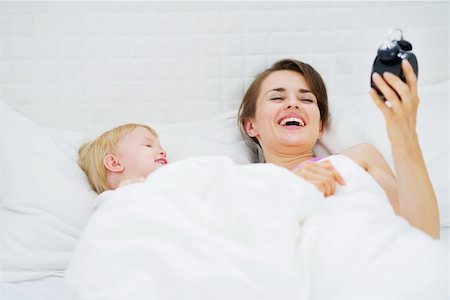 Baby and mother laying on bed and looking on alarm clock Stock Photo - Budget Royalty-Free & Subscription, Code: 400-06106770